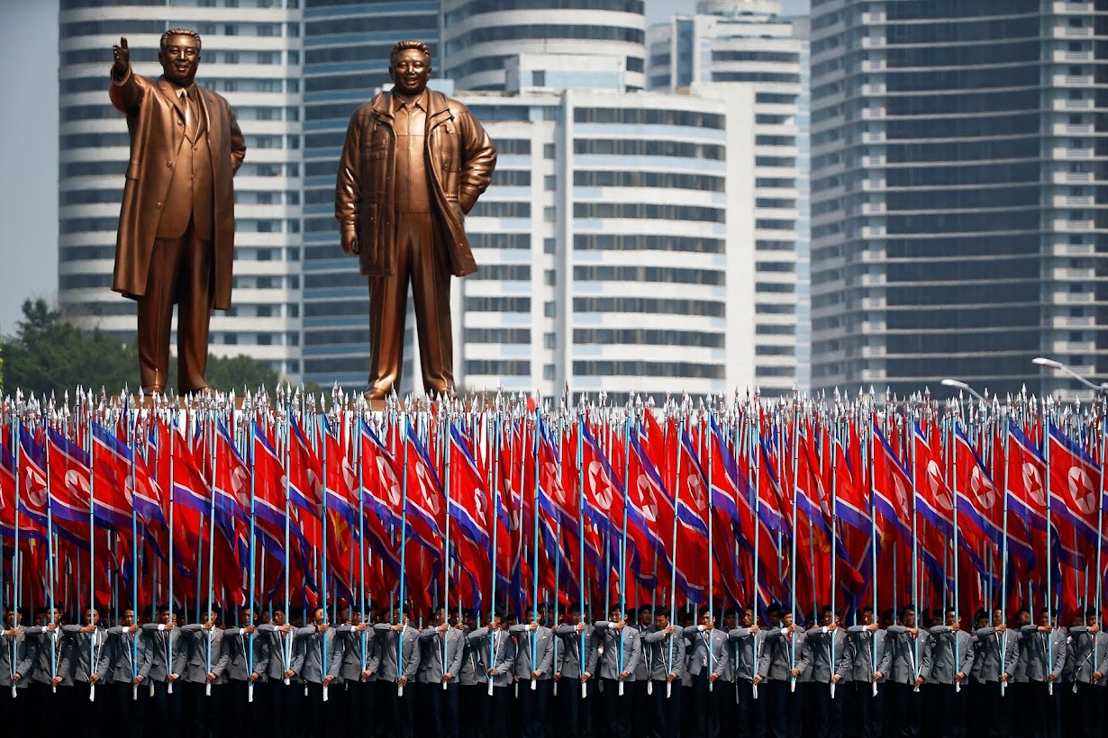 北朝鮮の大学の制服を着た旗を持つ男性たち。平壌で１５日撮影（２０１７年　ロイター/DAMIR SAGOLJ）